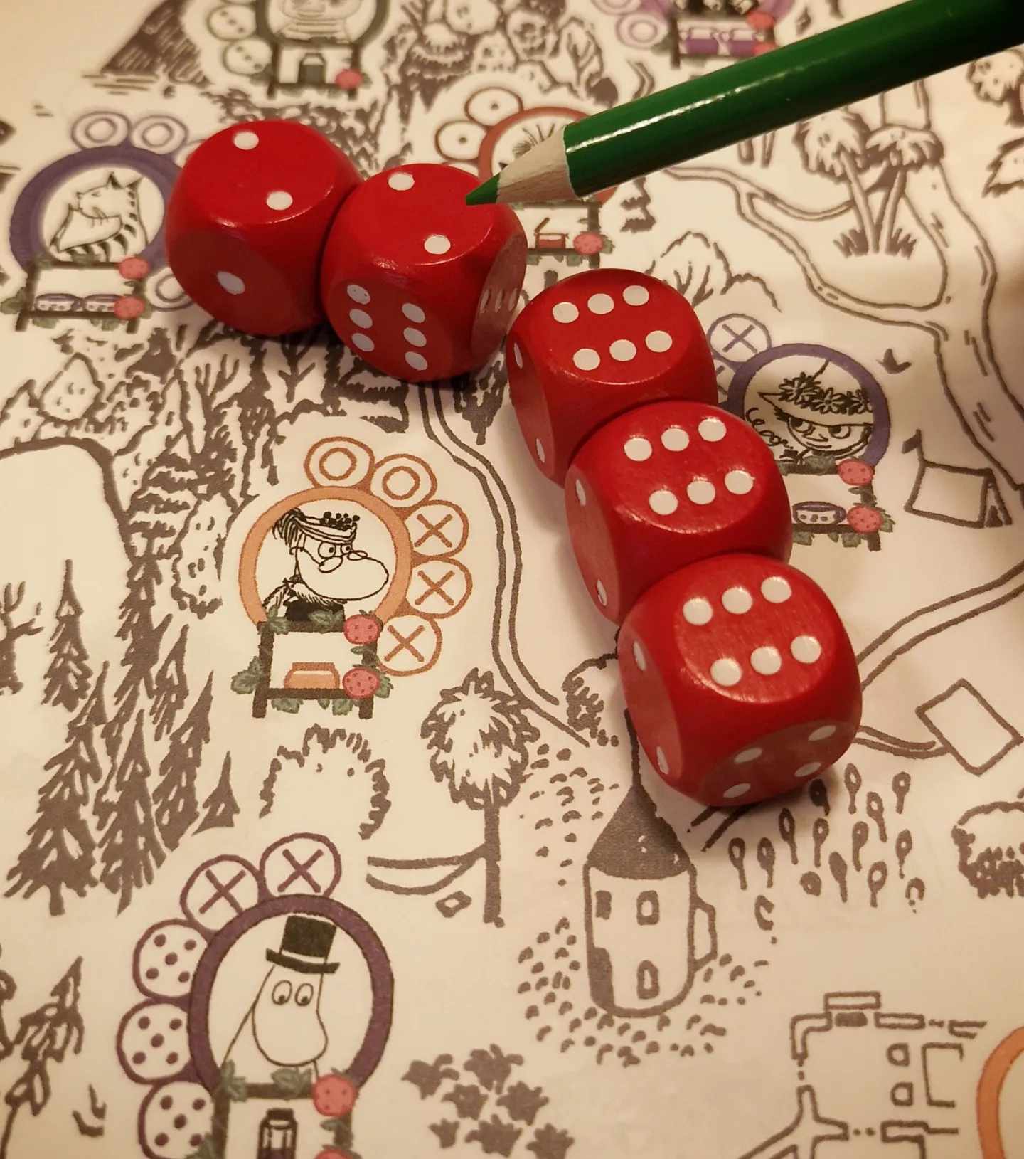 Close up of red dice and a green pen on top of tha game board.