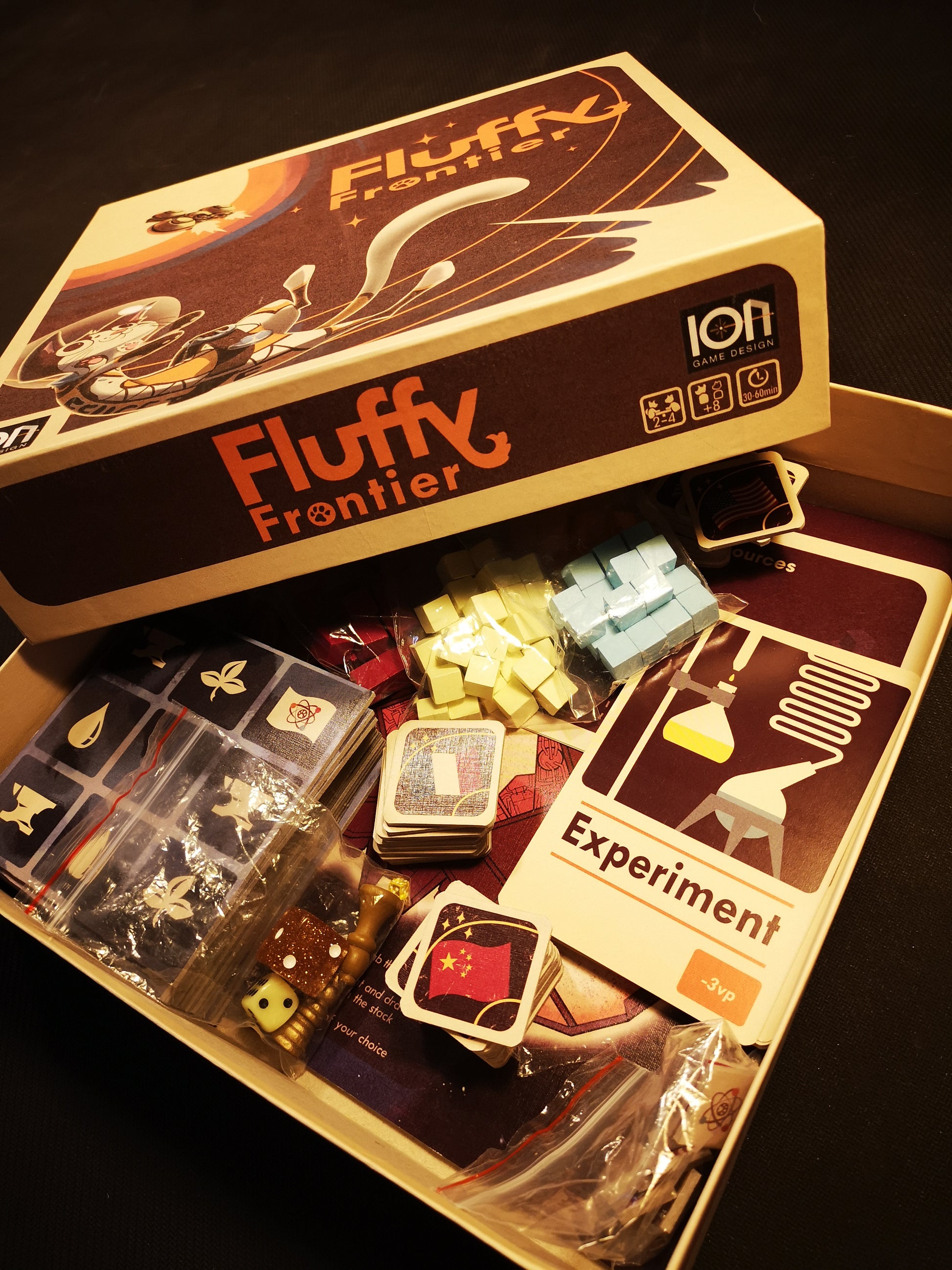 Close up of opened game box with game components stacked inside.
