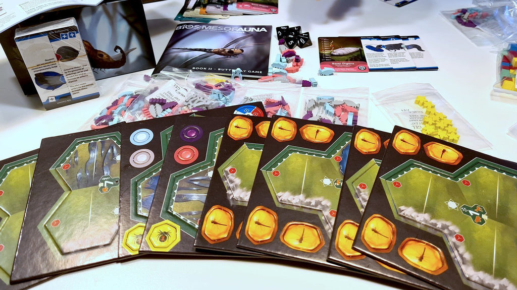 Bios: Mesofauna board game - Overview of game components. Including, Playing cards, fossil chit tokens, and rule book