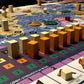 Bios: Origins (2nd edition board game) - Game board with elder pawns, city cuboids, and migrant figures game pieces organized in mid-game positions